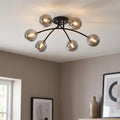 Six-light semi-flush ceiling fixture with black curved arms and smoked glass globes illuminated in a neutral room.