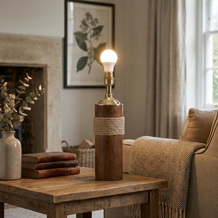 Oaks Moea wood and rope table lamp with an exposed bulb on a rustic side table in a cozy living room.