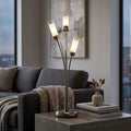 Oaks Oslo 3-light antique chrome table lamp with glowing frosted glass shades on a side table in a modern living room.