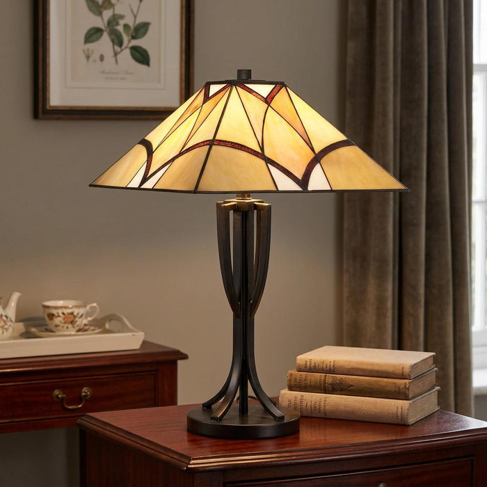 Oaks Portia Tiffany table lamp with a geometric glass shade on a wooden side table with books.