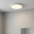 Round white flush bathroom ceiling light glowing in a modern tiled setting.