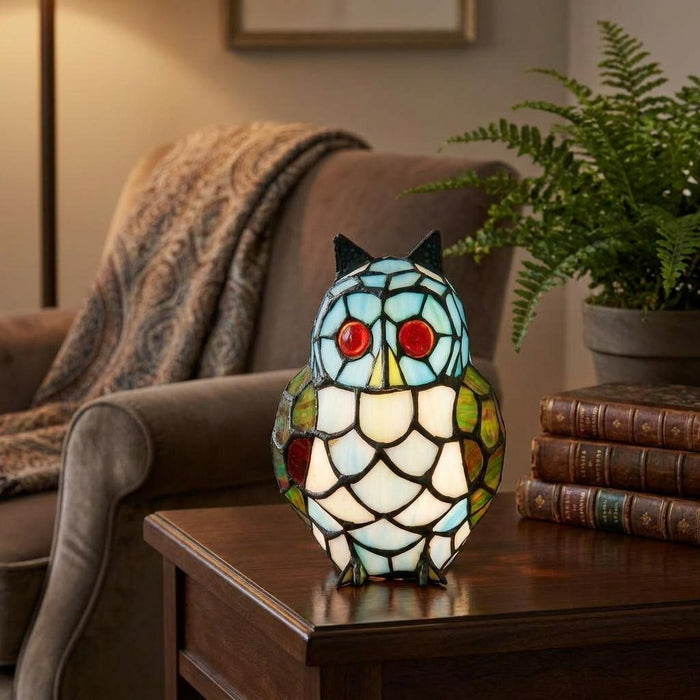 Tiffany-style owl table lamp with blue and white stained glass on a wooden side table in a cozy living room.