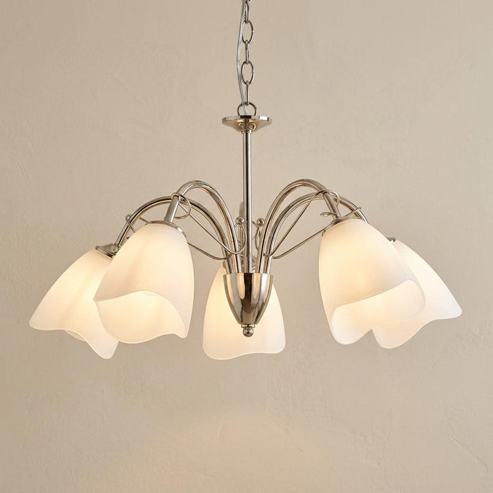 Modern five-light chrome chandelier featuring frosted glass shades with a wavy edge on curved arms.