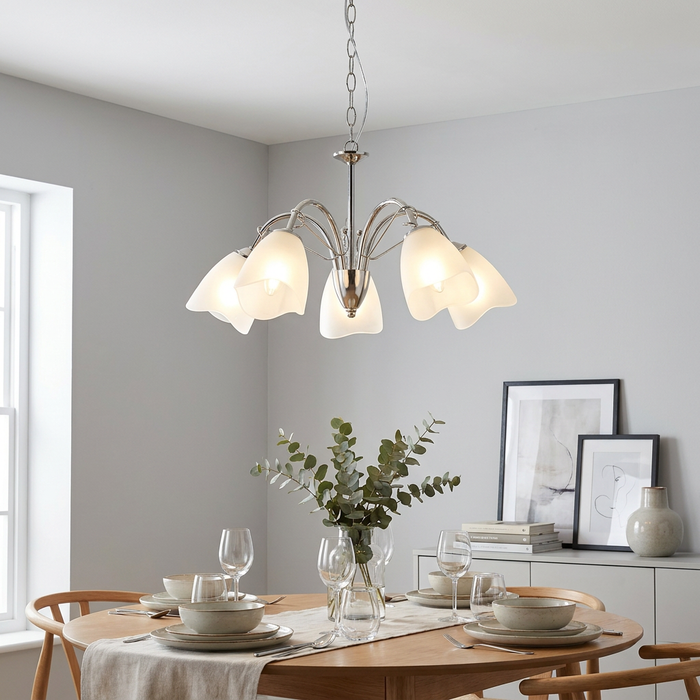 Oaks Turin 5-light chrome chandelier with frosted glass shades hanging above a minimalist wooden dining table.