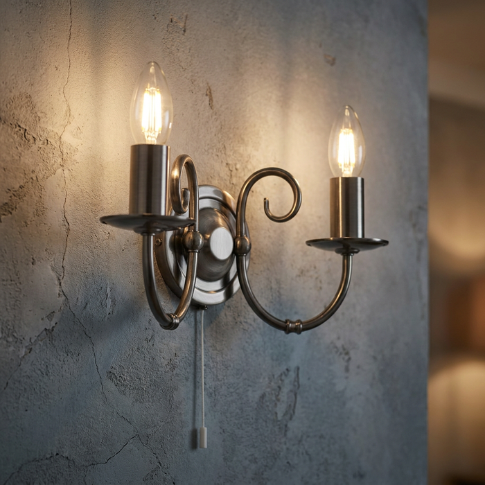 Oaks Tuscany double wall light in antique silver finish with glowing candle bulbs on a textured grey wall.