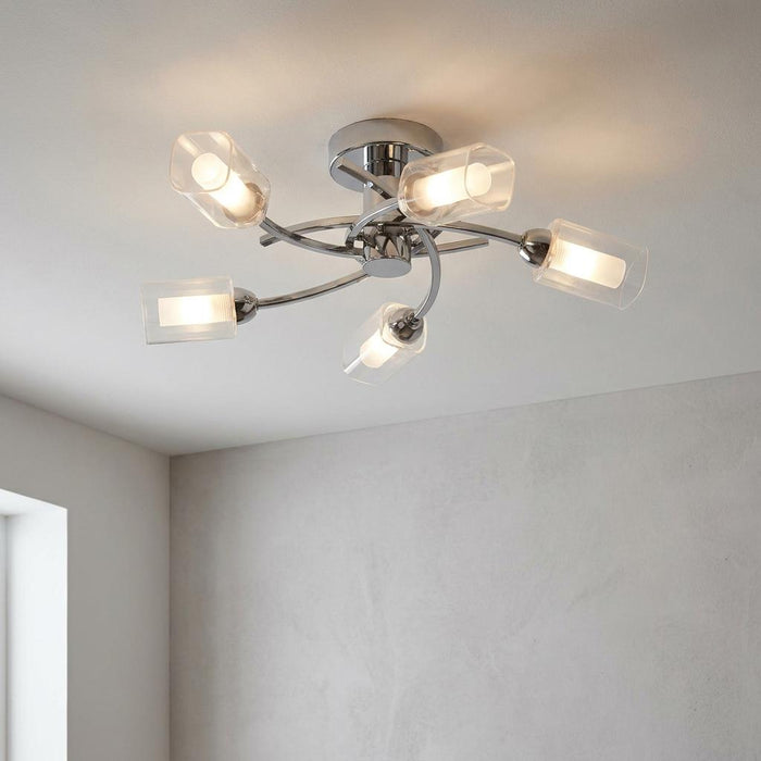 Ofira 5-light chrome flush ceiling light with curved arms and glowing frosted glass shades on a white ceiling.