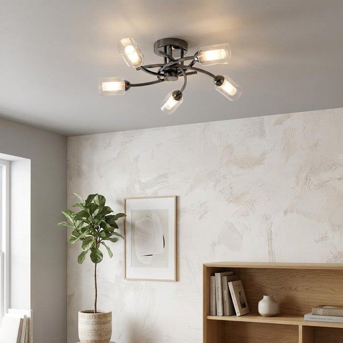 Ofira 5-arm black flush ceiling light with glass shades illuminating a minimalist room with a potted plant.