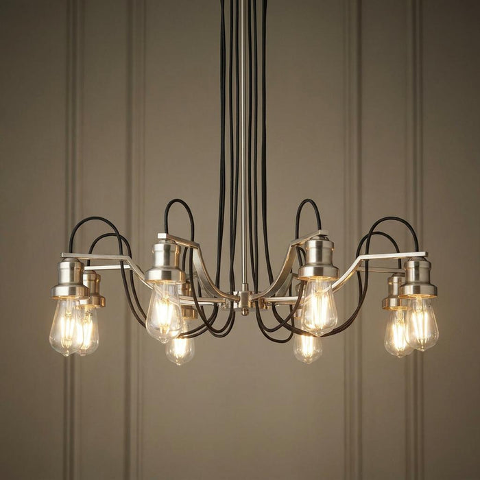 Eight-light silver pendant with looped black braided cables and glowing Edison bulbs against a paneled wall.