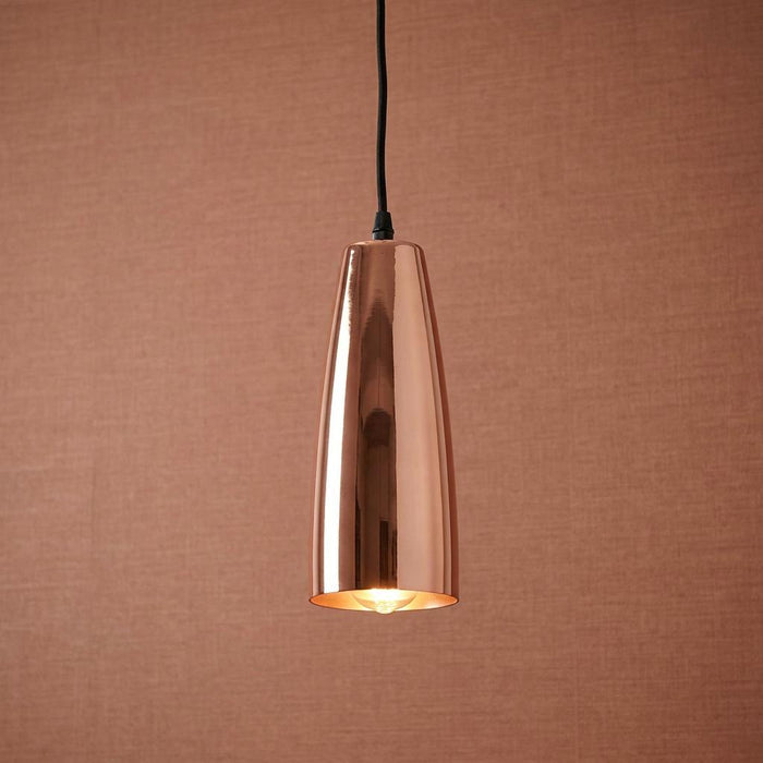 Polished copper cone-shaped pendant light hanging against a textured terracotta background.
