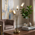 Oslo 3-light antique brass table lamp with frosted glass shades on a wooden sideboard in a stylish living room.