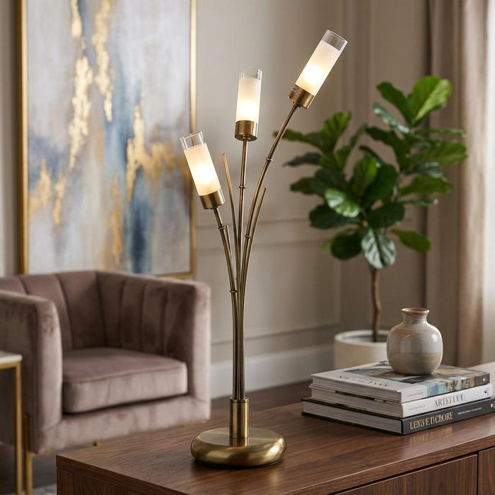 Oslo 3-light antique brass table lamp with frosted glass shades on a wooden sideboard in a stylish living room.