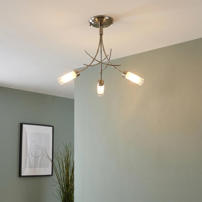 Antique chrome 3-light semi-flush ceiling fixture with curved arms and frosted glass cylinders in a light green room.
