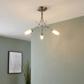 Antique chrome 3-light semi-flush ceiling fixture with curved arms and frosted glass cylinders in a light green room.