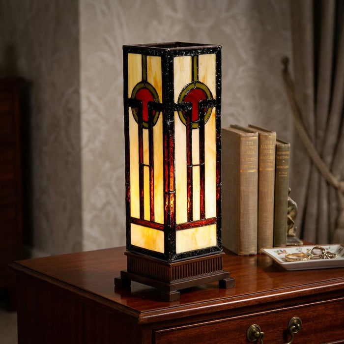 Oxford Tiffany Medium Square Table Lamp with geometric stained glass on a wooden desk next to books.