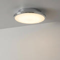 Circular chrome-rimmed flush ceiling light with a warm glow, mounted on a white ceiling.