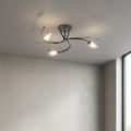 Pandora 3 light mirror black flush ceiling light with curved arms and glass shades illuminated in a minimalist room.