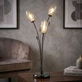 Pandora 3-light mirror black table lamp with illuminated glass shades on a wooden table in a modern living room.