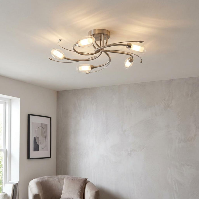 Pandora five-light antique chrome flush ceiling fixture with curved arms and glass shades in a modern living room.