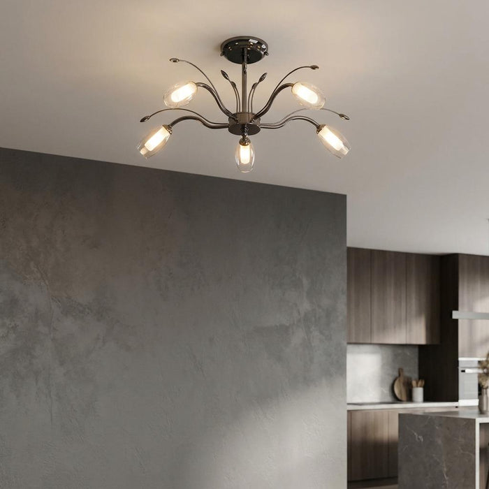 Pandora 5 light mirror black semi flush ceiling light with clear glass shades in a room with a grey textured wall.