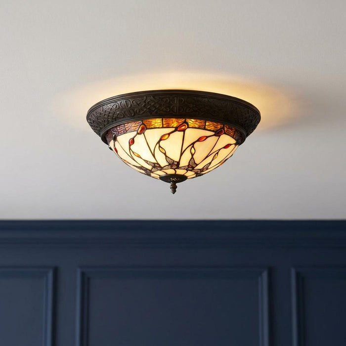 Warmly lit Papillon flush Tiffany ceiling light with an ornate bronze base and colorful leaded glass butterfly pattern.