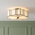 Geometric white Tiffany flush mount ceiling light with dark lead lines, illuminated against a white ceiling.