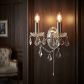 Paris 2-light silver wall sconce with glowing candle bulbs and hanging crystals on dark wood panelling.