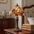 Perth Tiffany table lamp with a vibrant floral stained glass shade on a dark wood table.