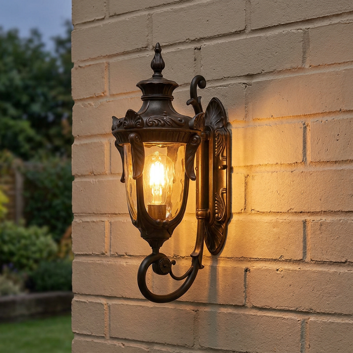 Ornate Philadelphia old bronze outdoor wall lantern with a glowing bulb mounted on a light brick wall.