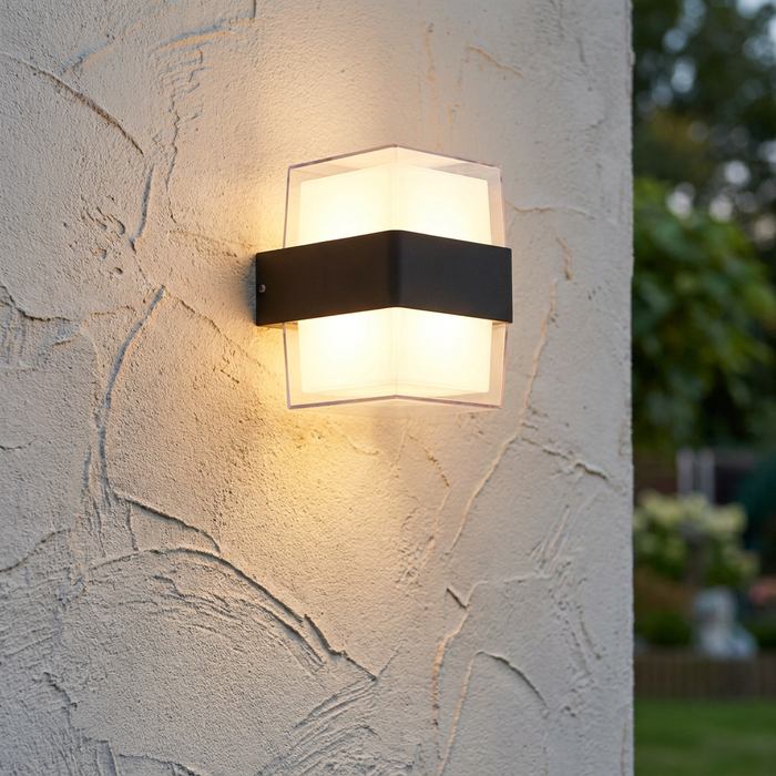 Modern black square LED up and down wall light glowing on a textured cream exterior wall.