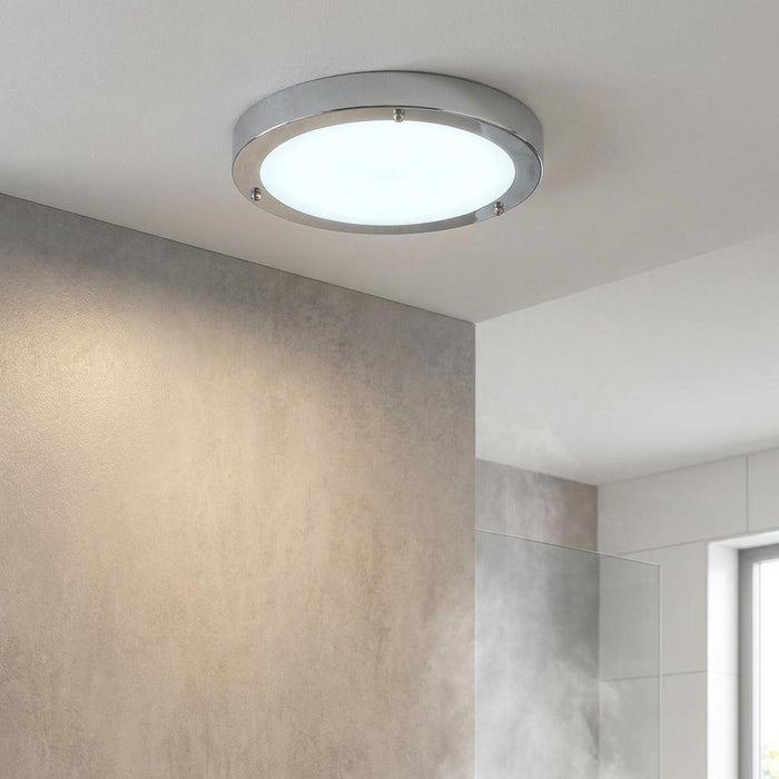 Circular chrome flush-mount LED bathroom light with frosted glass, illuminated on a white ceiling.