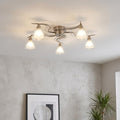 5-light antique chrome flush ceiling light with wavy arms and frosted glass shades, illuminated in a modern room.