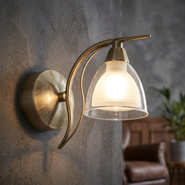 Portland Single Antique Brass Wall Light with a double glass shade glowing on a textured grey wall.