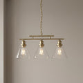 Antique brass 3-light ceiling pendant with clear conical glass shades and illuminated Edison bulbs on a plain wall.