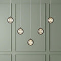 Quartz 5-light pendant with chrome-framed bubble glass shades staggered against a sage green paneled wall.