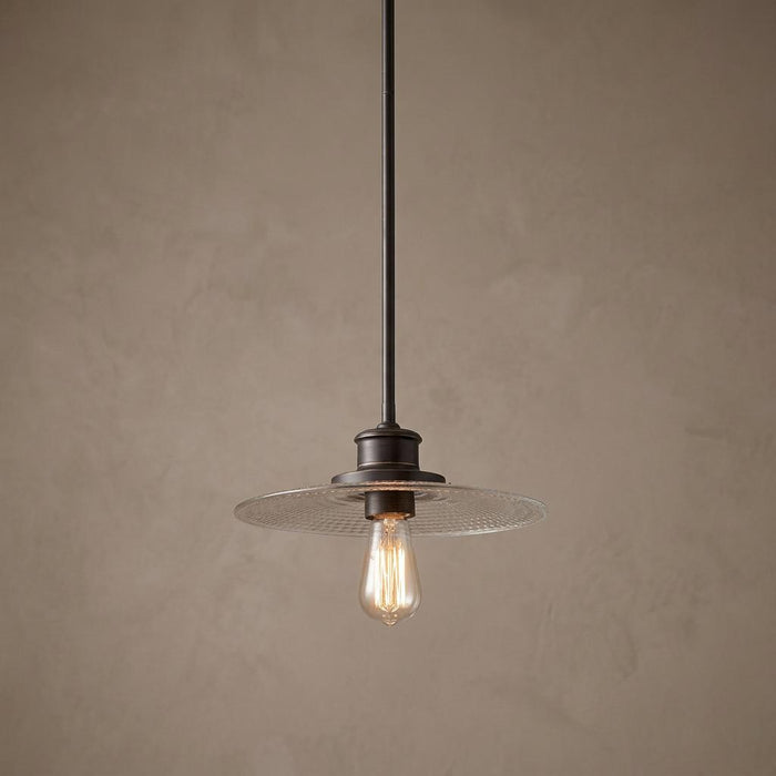 Quoizel Admiral bronze pendant light with a clear textured glass disk shade and a vintage-style bulb.