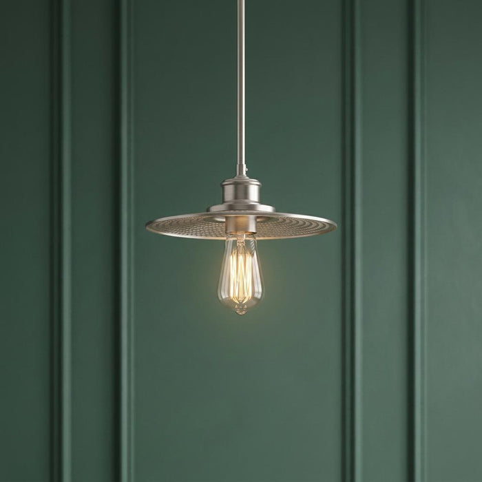 Industrial nickel pendant light with a mesh shade and Edison bulb against a dark green paneled wall.