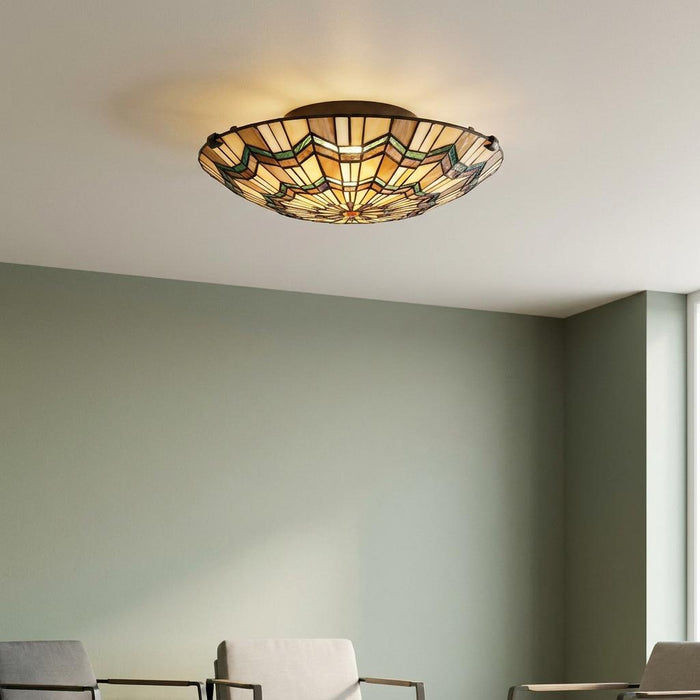 Glowing Quoizel Alcott Tiffany flush ceiling light with geometric stained glass in a sage green room.