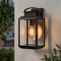 Bronze outdoor wall lantern with a glowing Edison bulb and copper reflector on a white textured wall.