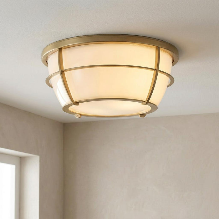Quoizel Chance 2-light brass bathroom flush mount with opal glass and a caged nautical design on a white ceiling.