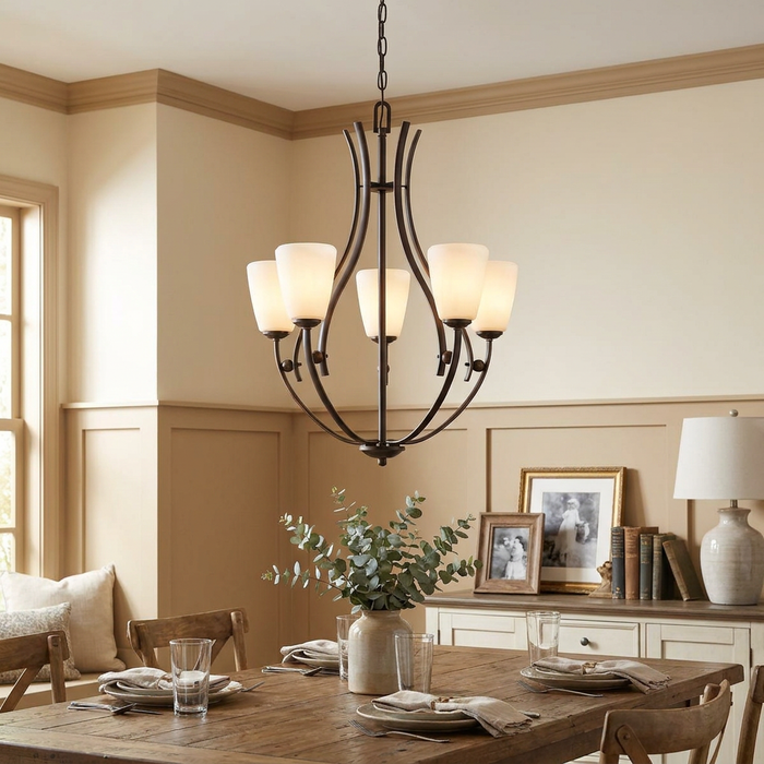 A 5-light bronze chandelier with opal glass shades illuminates a rustic wooden dining room table.