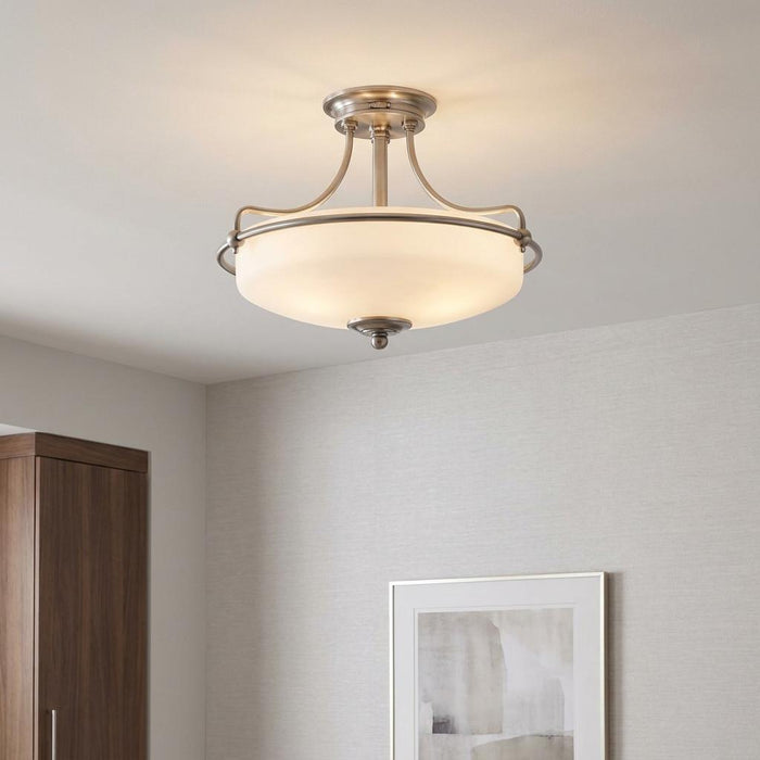 Brushed nickel semi-flush ceiling light with an opal glass bowl shade glowing in a neutral room.