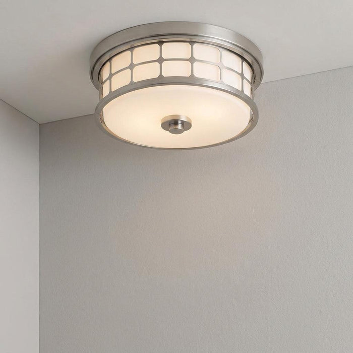 Brushed nickel flush mount light with a grid-pattern glass shade, installed on a white ceiling in a grey-walled room.