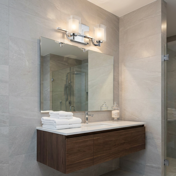 Quoizel Kolt 2-light chrome wall light with glass shades mounted over a bathroom mirror on a grey tiled wall.