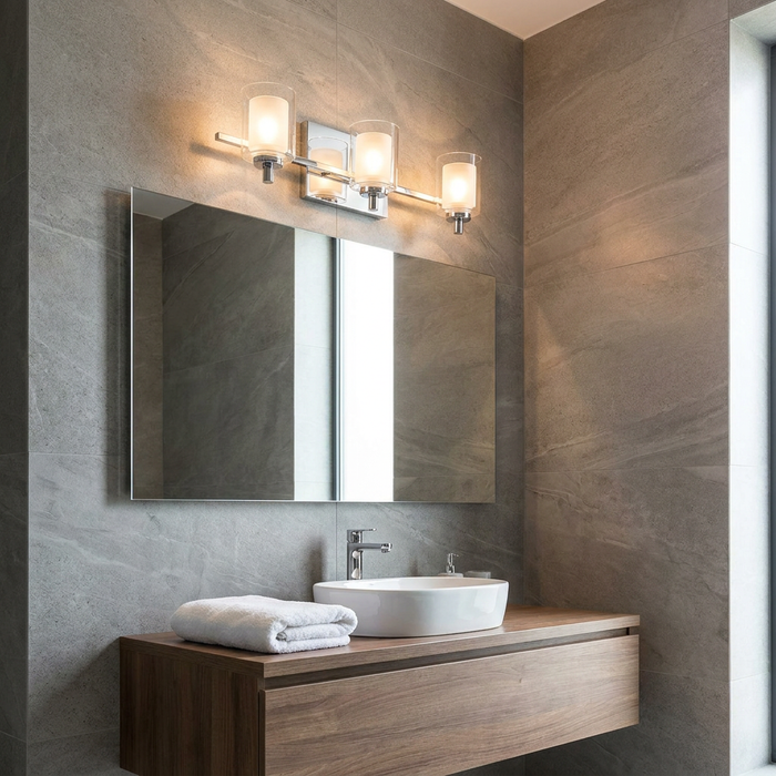 Modern Quoizel Kolt three-light chrome wall fixture with cylindrical glass shades above a bathroom mirror.