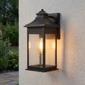 Quoizel Livingston bronze outdoor wall lantern with seeded glass mounted on a light-colored stucco wall.