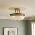 Quoizel Mantle semi-flush brass ceiling light with a textured glass bowl shade in a green-walled room.