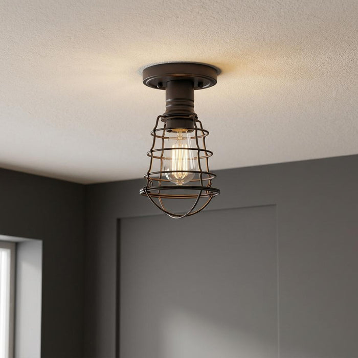 Industrial bronze semi-flush mount ceiling light featuring a wire cage and an exposed filament bulb.