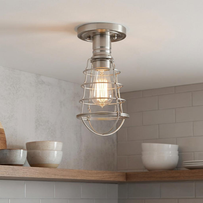 Industrial brushed nickel cage ceiling light with a warm Edison bulb above wooden kitchen shelves.