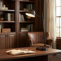Quoizel Spencer LED bronze table lamp illuminating a wooden desk with a notebook in a traditional home library.