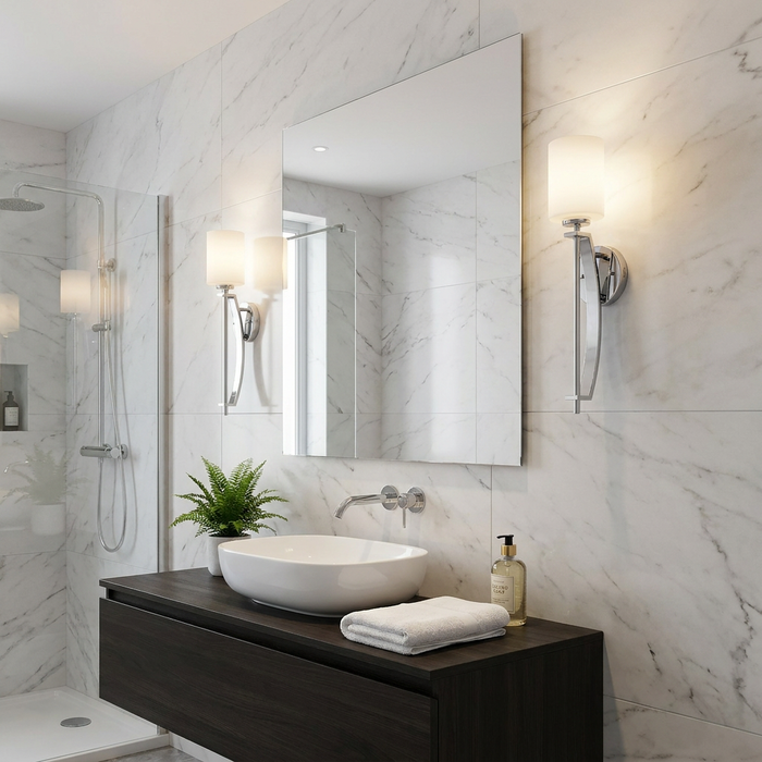 Polished chrome wall sconces with opal glass shades flanking a mirror in a modern marble-tiled bathroom.